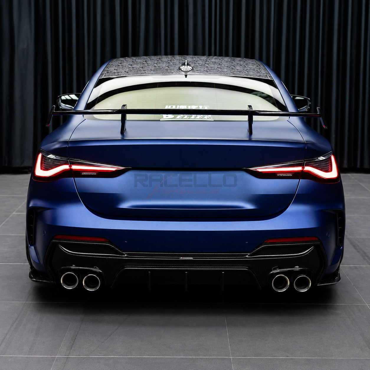 BMW 4er G22 in Blau mit montiertem T4X1 Dry Carbon Heckspoiler, Heckansicht
